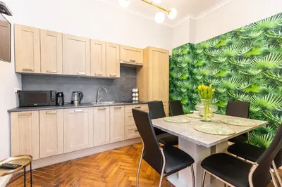 a kitchen with a table with chairs and a green wall at Vintage Bracka Apartment in Kraków