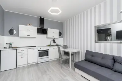a white kitchen with white cabinets and a table at Cegielniana Grey Studio by BookingHost in Kraków
