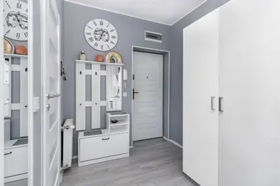 a hallway with white cabinets and a clock on the wall at Cegielniana Grey Studio by BookingHost in Kraków