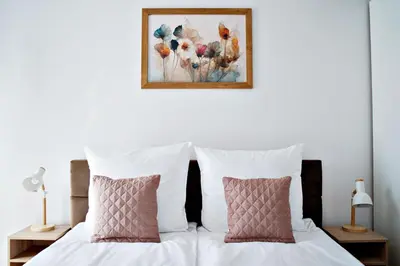 a bed with two pillows and a painting on the wall at Apartament Bulwary 3 in Oświęcim