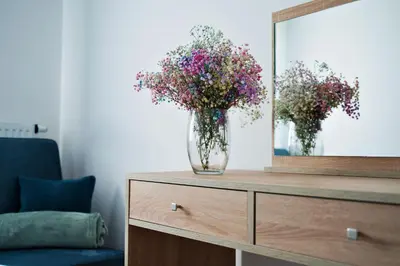 a dresser with a mirror and a vase of flowers at Apartament Bulwary 3 in Oświęcim