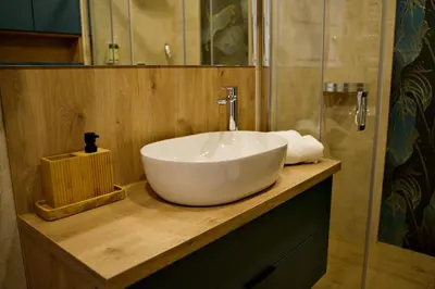 a bathroom with a white sink on a wooden counter at Apartament Bulwary 3 in Oświęcim