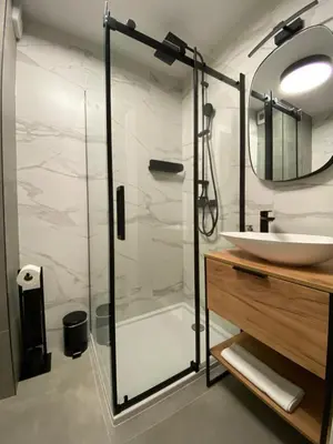 a bathroom with a glass shower and a sink at Vistula Avenue Apartment free Parking in Kraków