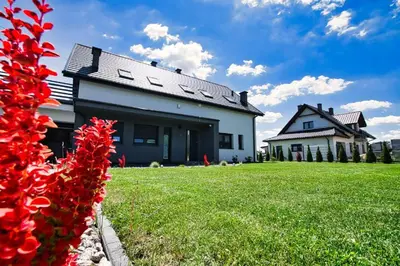 a house with red flowers in the yard at Apartamenty Izabell by Housine in Zator