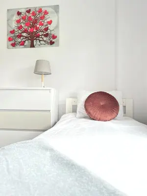 a white bedroom with a white bed with a red pillow at Apartamenty Izabell by Housine in Zator