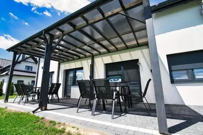 a patio with a table and chairs under a pergola at Apartamenty Izabell by Housine in Zator