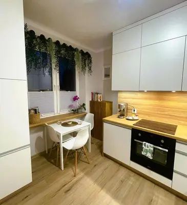 a kitchen with white cabinets and a table and a table and chairs at MR HOME APARTMENTS - Mogilska in Kraków