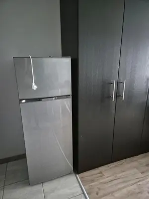 a stainless steel refrigerator in a kitchen next to cabinets at Apartament Bunsha Kraków in Kraków