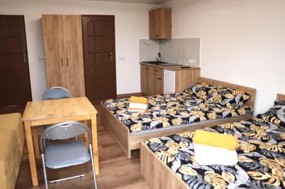 a room with three beds and a table and a kitchen at Apartamenty Zator Energy Rest in Zator