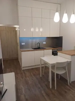 a kitchen with white cabinets and a table and a sink at Studio Przemyska Cracow's Kazimierz in Kraków