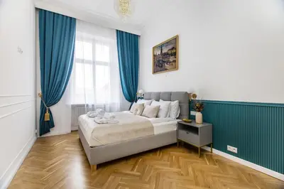 a bedroom with a bed and blue curtains at BOB Elite Apartments in Kraków