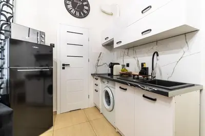 a white kitchen with a sink and a dishwasher at Old Town Studio Wawel in Kraków
