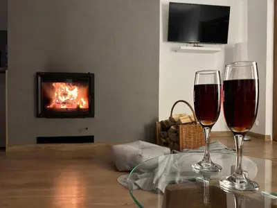 two glasses of wine sitting on a table in front of a fireplace at Bąbelkowa Chata Beskidy Domek z Balią Jacuzzi in Gilowice
