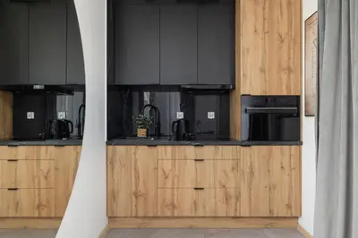 a kitchen with black appliances and wooden cabinets at Rakowicka Modern Studio in Downtown Cracow by Rent like home in Kraków