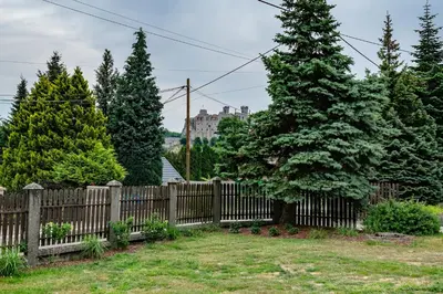 a wooden fence with trees and a castle in the background at Willa Olimpia in Podzamcze