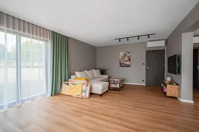 a living room with a white couch and a large window at Willa Olimpia in Podzamcze