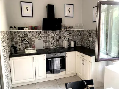 a kitchen with white cabinets and a sink and a mirror at YOONIK APARTMENTS in Kraków