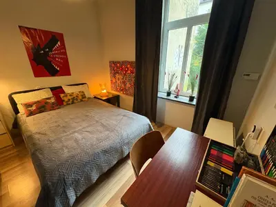 a bedroom with a bed and a table and a window at YOONIK APARTMENTS in Kraków