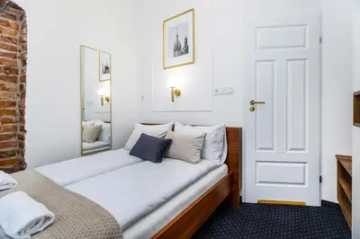 a bedroom with a bed with white sheets and a mirror at BoB Elite - Szpitalna in Kraków