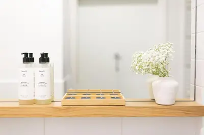 a shelf with two bottles and a vase with flowers at Malila Premium Apartments Cracow City Center Pawia 34 in Kraków