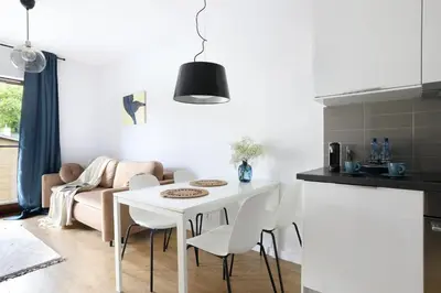 a kitchen and living room with a white table and chairs at Malila Premium Apartments Cracow City Center Pawia 34 in Kraków