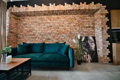 a living room with a green couch against a brick wall at Apartament Zator 5 by Housine in Zator