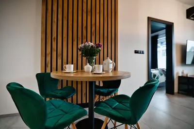 a table with green chairs and a vase of flowers at Apartament Zator 5 by Housine in Zator