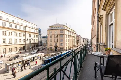 a train on a track in a city with buildings at Apartamenty Starowiślna 1, Kraków Main Square in Kraków