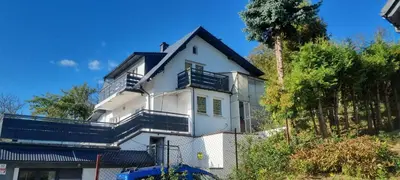 a white house with black balconies and a fence at Noclegi u Ewusi in Januszowice