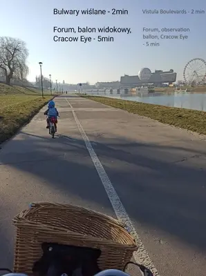 a person riding a bike down a road with a basket at Miejska Cisza Urban Silence in Kraków