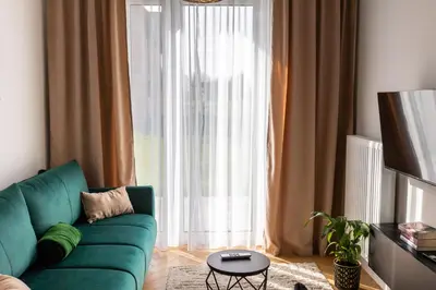a living room with a green couch and a large window at DS Apartamenty Jaśminowa in Zator