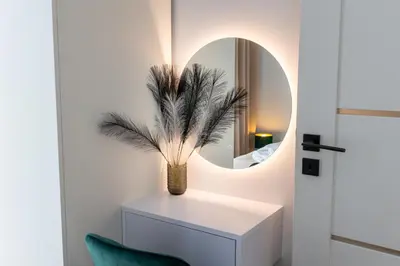 a room with a mirror and a vase with a plant at DS Apartamenty Jaśminowa in Zator