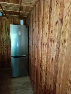 a stainless steel refrigerator in a room with wooden walls at Noclegi u Ewusi 2 in Januszowice