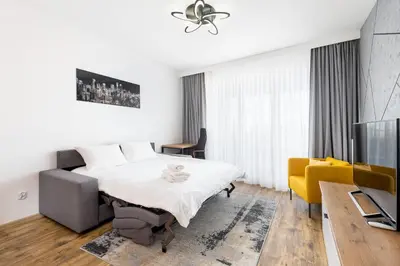 a white bedroom with a bed and a yellow chair at Wiślane Tarasy 2 0 Chic Studio by BookingHost in Kraków