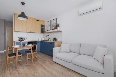 a living room and kitchen with a couch and a table at Modern Apartment in Kraków Podgórze by Noclegi Renters in Kraków
