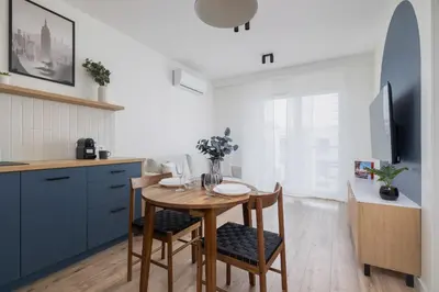 a kitchen with a wooden table with chairs and a dining room at Modern Apartment in Kraków Podgórze by Noclegi Renters in Kraków