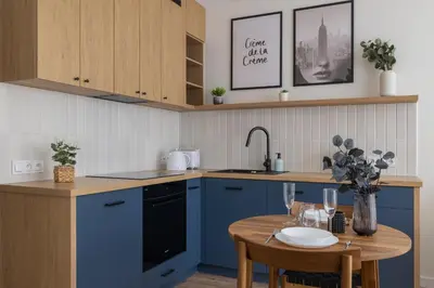 a kitchen with blue cabinets and a wooden table at Modern Apartment in Kraków Podgórze by Noclegi Renters in Kraków