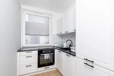 a white kitchen with white cabinets and a window at Bronowice Comfy Studio by BookingHost in Kraków