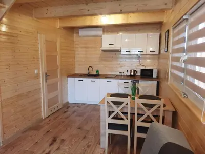 a kitchen with white cabinets and a table with chairs at Energy4YOU Zator in Zator