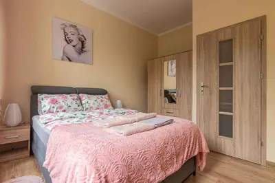 a bedroom with a bed with a pink bedspread at Apartament 45m2 - Sunny&Quiet - VERY CLOSE to Auschwitz Museum ! in Oświęcim