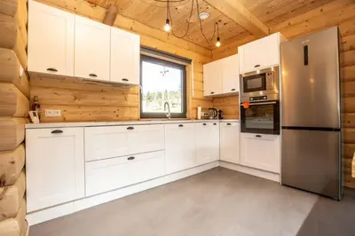 a kitchen with white cabinets and a refrigerator at Gorczański dom z bali w górach in Poręba Wielka