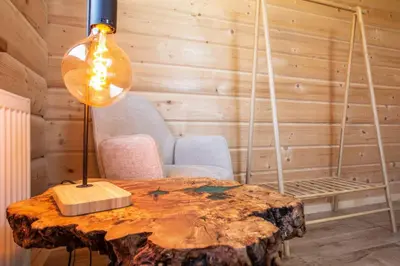 a table with a lamp on top of a tree stump at Gorczański dom z bali w górach in Poręba Wielka