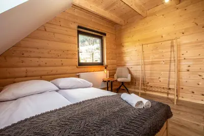 a bedroom with a bed in a wooden cabin at Gorczański dom z bali w górach in Poręba Wielka