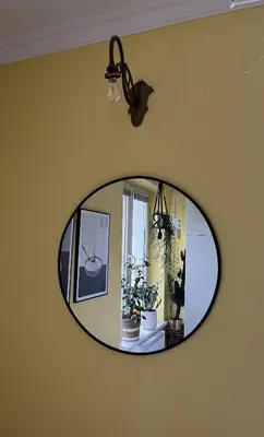 a round mirror on a yellow wall with a plant at Greenthumb Praska in Kraków