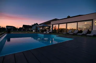 a house with a swimming pool at dusk at Dom z jacuzzi do 10 osób Zator Willa LuxHouse in Zator