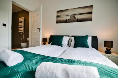 a bedroom with a large bed with green and white sheets at Dom z jacuzzi do 10 osób Zator Willa LuxHouse in Zator