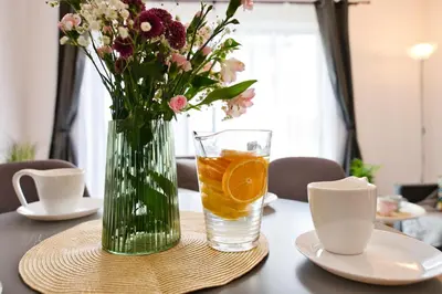 a vase of flowers and a glass of water on a table at Domki na Sosnowej by Housine in Zator