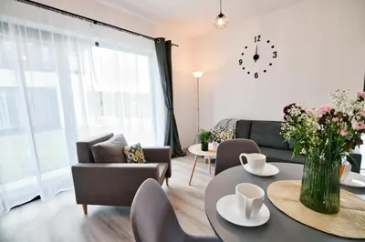 a living room with a table and chairs and a clock at Domki na Sosnowej by Housine in Zator