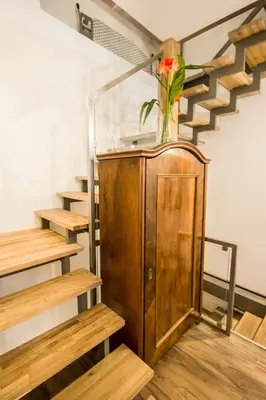a vase of flowers on top of a wooden cabinet with stairs at Sewa Apartments in Kraków
