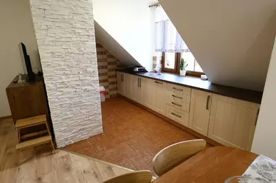 an attic kitchen with a table and a window at Rabczański Apartament in Rabka-Zdroj